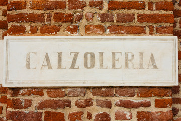  old sign shoe repair written in italian language/ sign made of cement indicating the writing shoe repairer  on a bricks wall