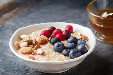 Home oatmeal with cranberries and blueberries. White plate, hone