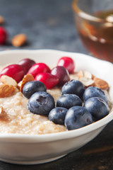 Home oatmeal with cranberries and blueberries. White plate, hone