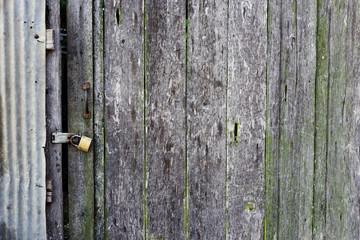 Old weathered wooden door made from planks. With rusty lock