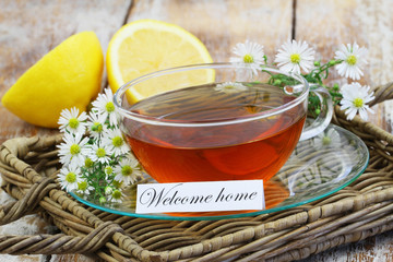 Welcome home card with cup of chamomile tea and fresh chamomile flowers
