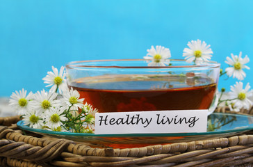 Healthy living card with cup of chamomile tea on blue background with copy space

