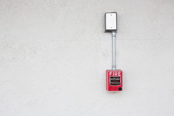 Red fire alarm switch at white wall