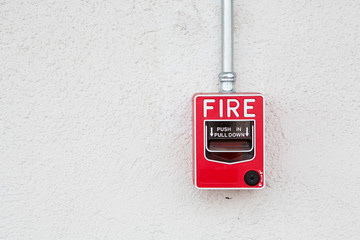 Red fire alarm switch at white wall