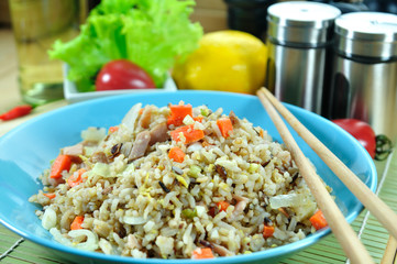 Chicken ham fried rice with carrot in blue plate set up on table
