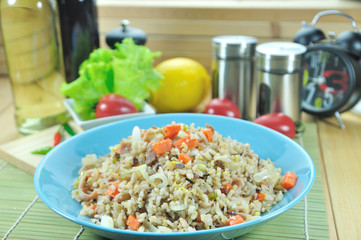 Chicken ham fried rice with carrot in blue plate set up on table