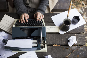 
woman typing on a typewriter - obrazy, fototapety, plakaty