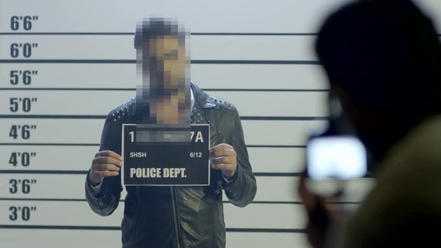 Arrested man standing by the police wall. Shot on RED EPIC Cinema Camera in slow motion.