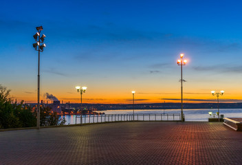 Embankment illuminated by lanterns at sunset