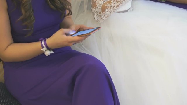 Bride with girlfriend browse photos on smartphones