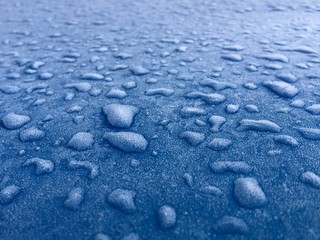 Frozen water drops beads on blue metal