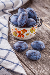 plum in a cup on a wooden board