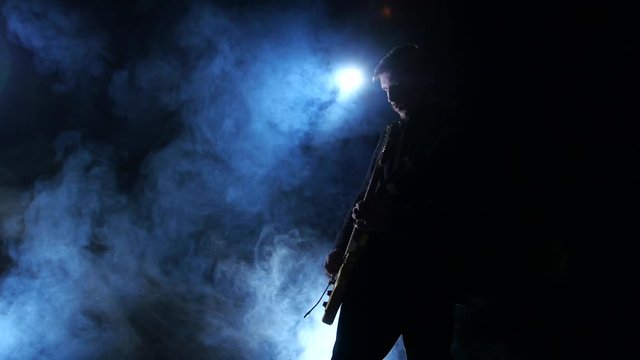 Bass guitar. Playing professional musician in a dark smoke studio