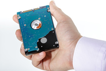 Man's hand holds a 2.5 inch hard drive. View of the backside HDD, from the PCB. Isolated on white background.