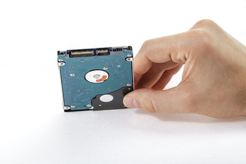 Man's hand holds a 2.5 inch hard drive. View from the rear of the drive, SATA connector up. Isolated on white background.