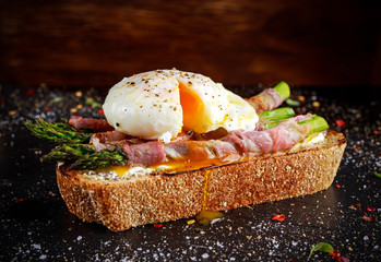 Grilled Toast witch Asparagus, Poached egg, bacon on stone background