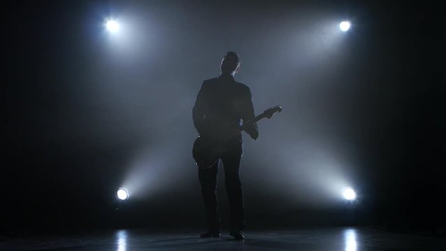 Guitarist in a dark studio plays a fast melody