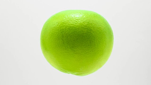 Green grapefruit  suspended in the air rotates in loop   