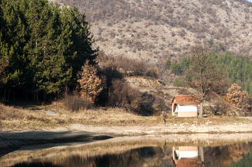 Small orthodox chapel and its reflection on lake waters in autumn