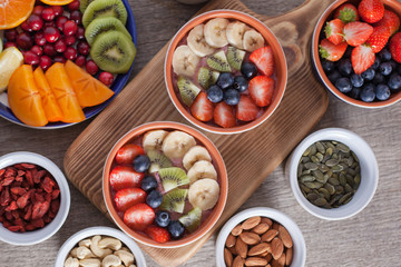 Smoothie  with fruits and berries on the grey wooden table, with variety of fruits and nuts around, selective focus, top view