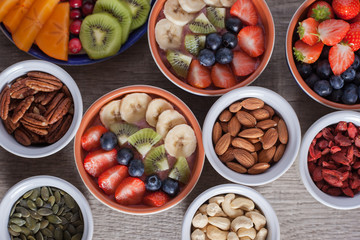 Smoothie  with fruits and berries on the grey wooden table, with variety of fruits and nuts around, selective focus, top view