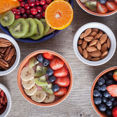 Smoothie  with fruits and berries on the grey wooden table, with variety of fruits and nuts around, selective focus; top view