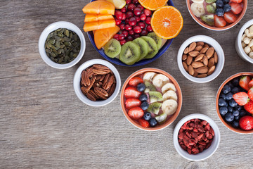 Smoothie  with fruits and berries on the grey wooden table, with variety of fruits and nuts around, selective focus; top view