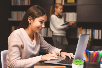 Smiling girl typing on laptop