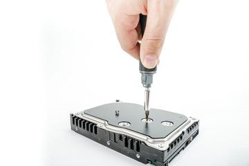 Hand repairman unscrews the 3.5 inch hard drive cover with a screwdriver. Isolated on white background.