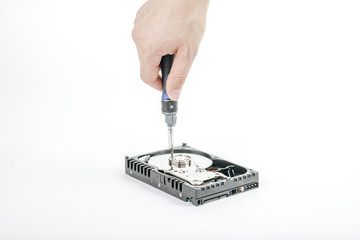 Hand repairman unscrews the cover of the engine of the open 3.5 inch HDD  with a screwdriver. Isolated on white background.