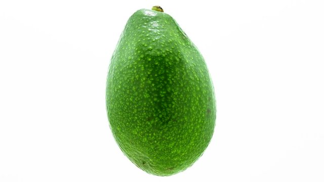 Green avocado suspended in the air rotates in loop    