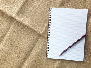 Open note book and pencil on sackcloth