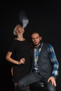 young woman smoking electronic cigarette near a man