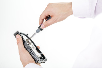 Man's hand holds open 3.5 HDD. His another hand unscrews the cover of the engine with a screwdriver. Isolated on white background.