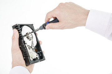 Man's hand holds open 3.5 HDD. His another hand unscrews the cover of the engine with a screwdriver. Isolated on white background.