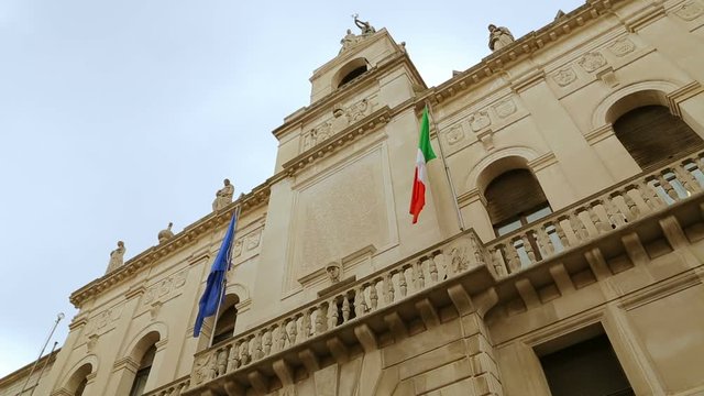 Italian and European flags on the historic building of Town Hall of Padua. Palazzo Moroni, Comune di Padova, shooting from the bottom of. Palazzo Moroni - seat of the Municipality of Padua, Italy