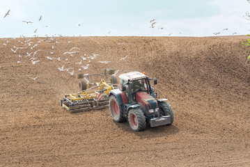 Large view on the tractor harrowing the field in spring season