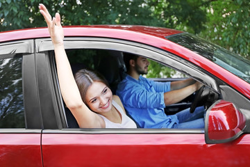 Pretty young woman waving through open car window