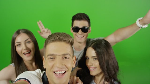 Happy friends taking selfie and demonstrating different versions of emotions and poses on green screen. With photo camera flash light. Shot on RED EPIC DRAGON Cinema Camera. 