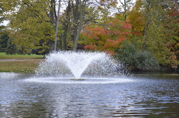Beautiful fountain splashing in the park pond on a summer day