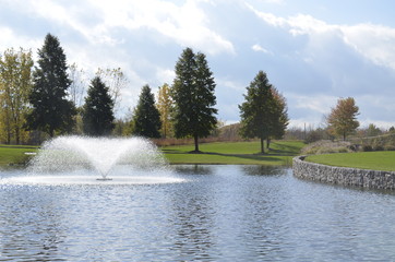 Beautiful fountain splashing in the park pond on a summer day