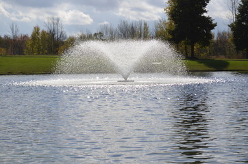 Beautiful fountain splashing in the park pond on a summer day
