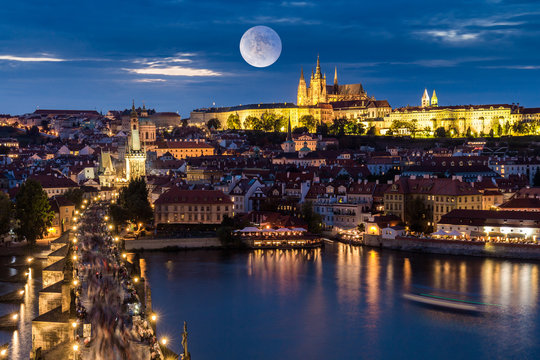 Full moon over Prague skyline at night. Magnificent Charles brigde and Prague castle at night along the River Vltava. Czech Republic