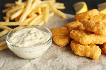 Tasty nuggets with fries and sauce on table