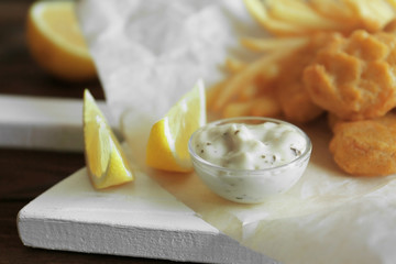 Bowl with sauce and lemon slices on table, closeup