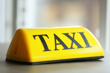 Yellow taxi roof sign on gray table, closeup