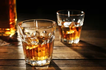 Gordijnen Glasses of whisky on wooden table closeup © Africa Studio
