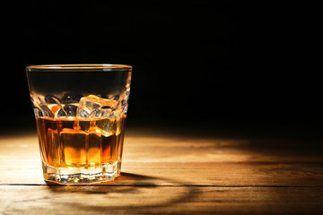 Glass of whisky on wooden table closeup