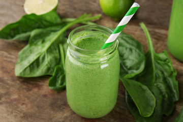 Fresh milkshake with spinach on wooden table closeup