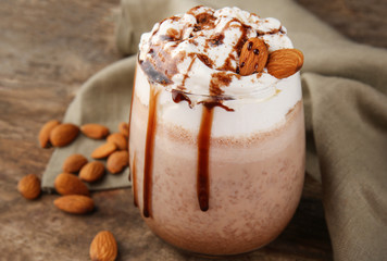 Fresh milkshake with almond on wooden table, closeup